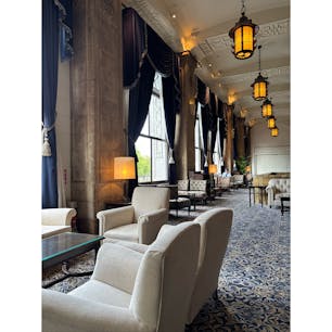 #横浜　山下公園に面して建つホテルニューグランド本館2階ロビーを見学して来ました。

高い天井と窓、ネイビーのドレープカーテンやカーペット、マホガニー木材の深い色味が調和するクラシックホテルならではの美しい内装✨天女が飛ぶ様子の綴織や鳳凰（フェニックス）モチーフの装飾、灯籠を思わせる照明など和の要素もある和洋折衷のデザイン。ウェディングフォトでも有名な青い絨毯敷の階段もしっかり写真におさめました📸

ホテルニューグランドは1927年、関東大震災の復興のシンボルとして誕生。復興への願いを込めロゴマークをフェニックスとしたそうです。

#クラシックホテル